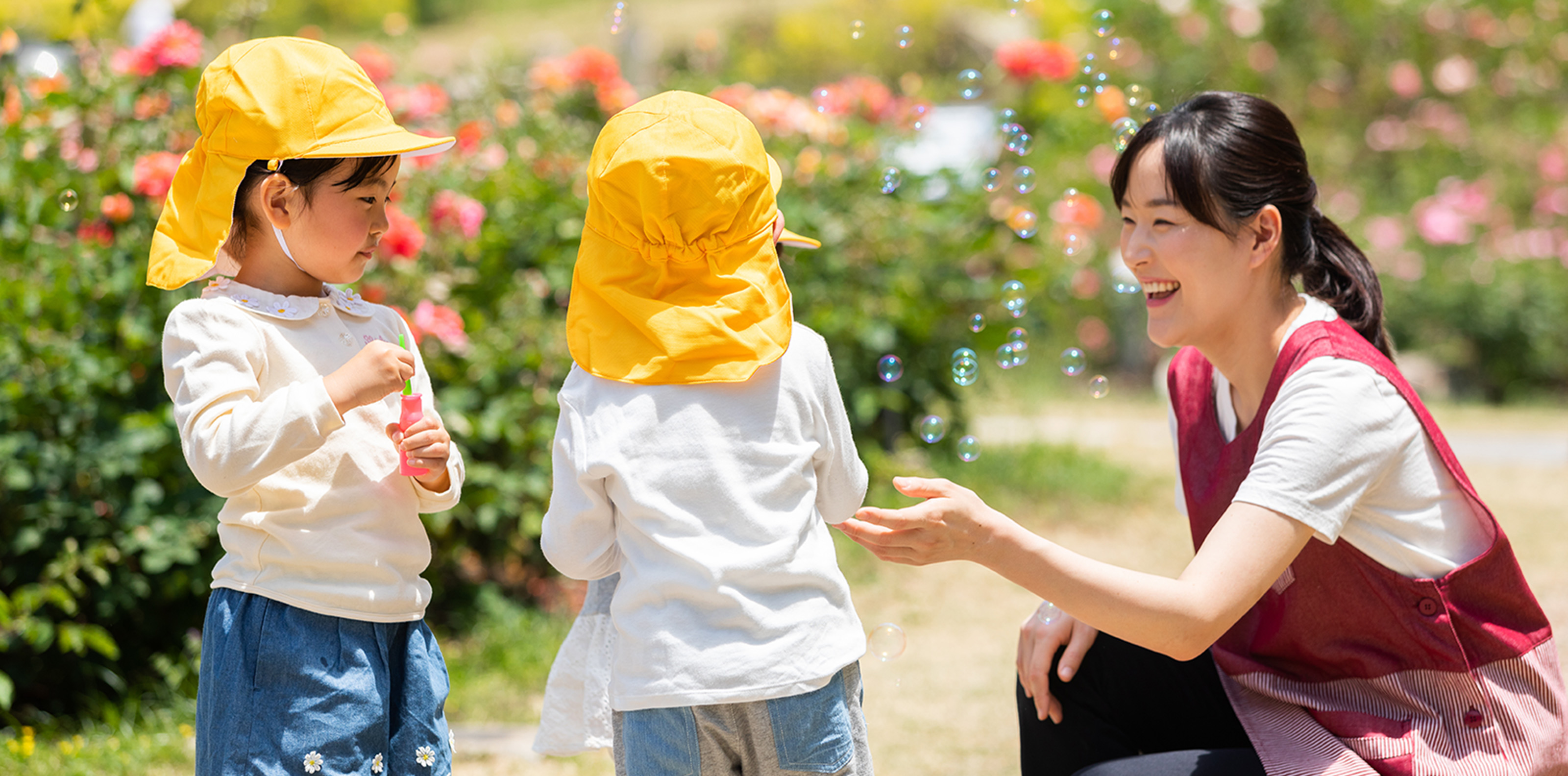 園児とシャボン玉遊びをする笑顔の先生
